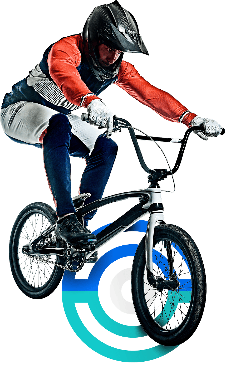 In the image, a male cyclist is riding a BMX. He is wearing a helmet and is dressed in a blue, red and white uniform, apart from gloves. He is close to make a stunt.