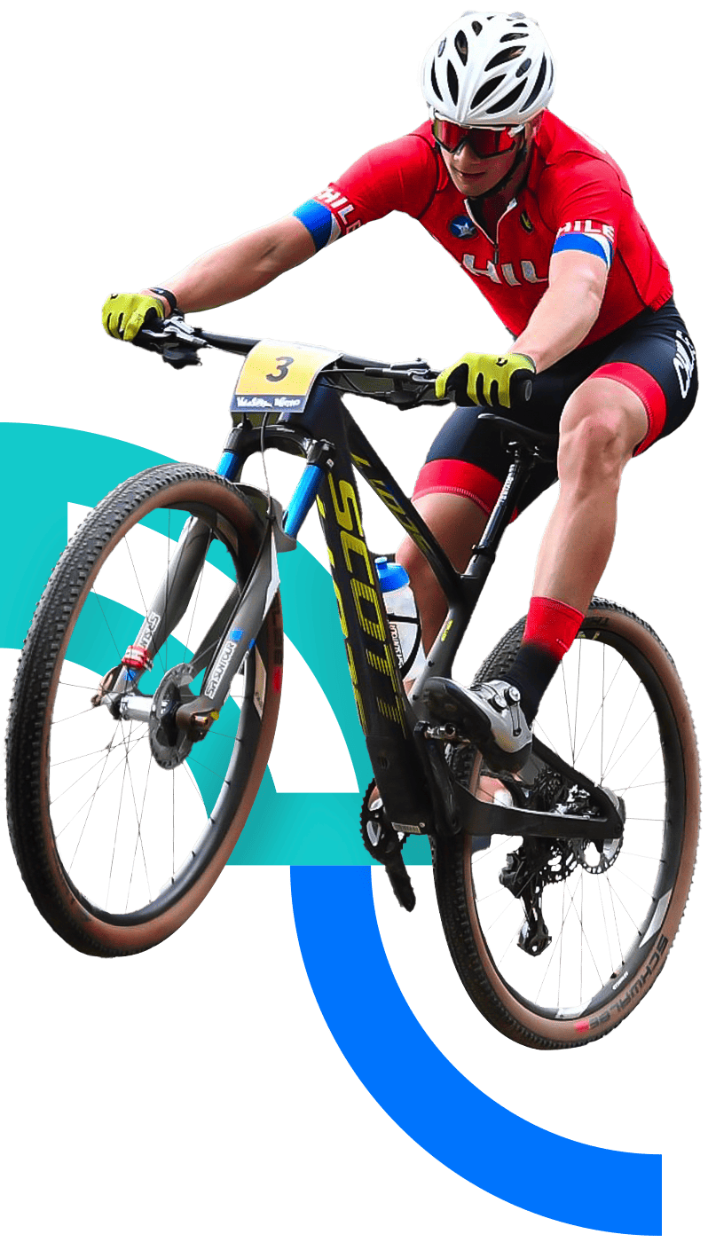 In the picture, a male mountain bike cyclist is driving on a competition. He is using the Chilean uniform.
