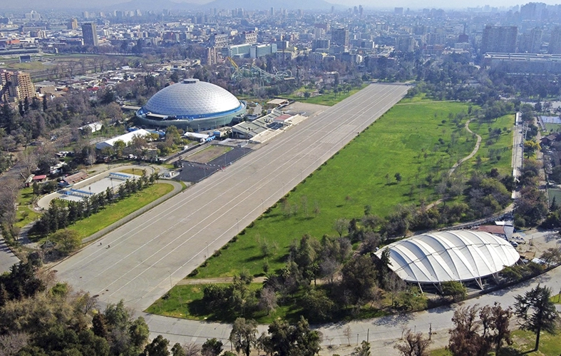 On the image, an aerial shot of the city of Santiago can 
                            be appreciated. There are highways connected and 
                            buildings. Also, there is a hill and, at the back, the Los 
                            Andes mountain range.