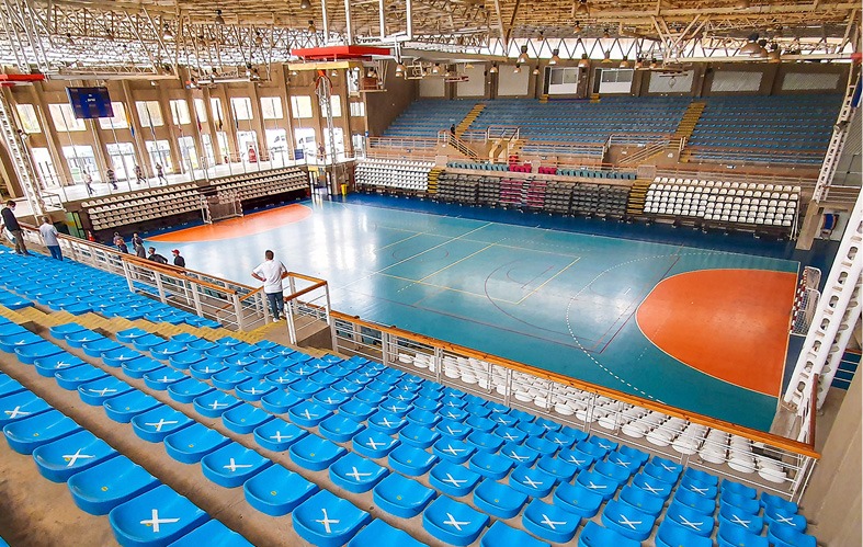 On the image a high-rise view of the blue color stands of 
                            the Multisport Gym of Viña del Mar is appreciated. A 
                            person, on their back, is watching a group that is on the 
                            court where handball will be played.
